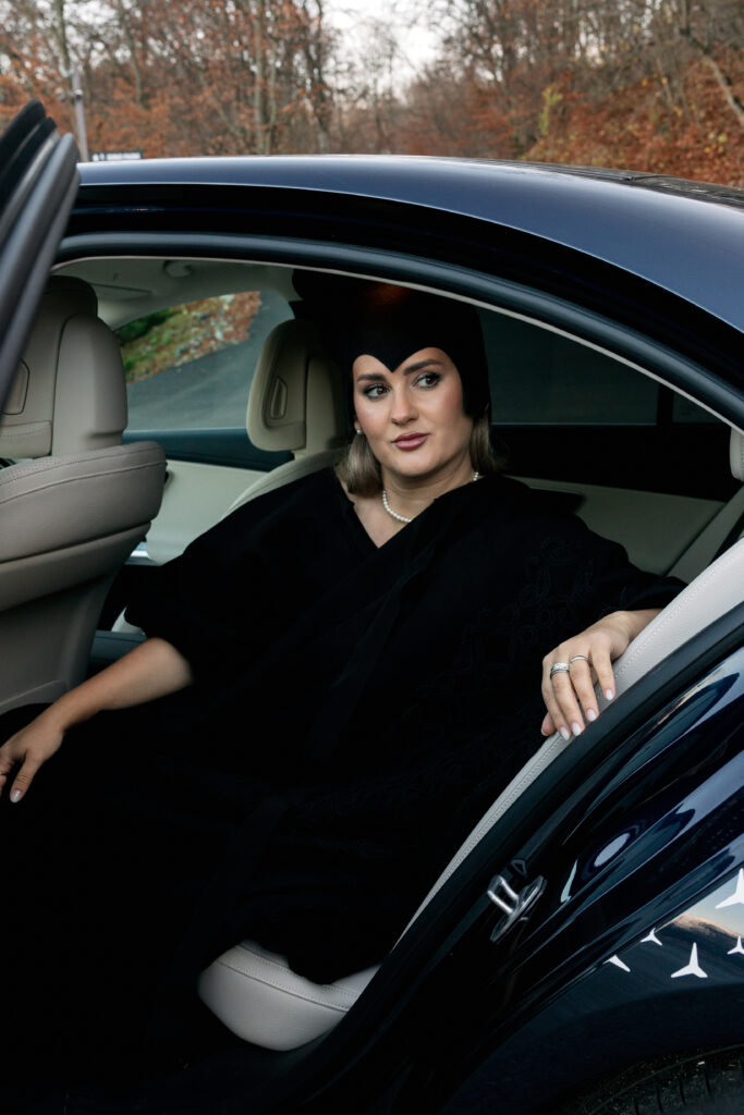 În imagini, personajul stă în spate — o alegere naturală pentru cineva obișnuit să lucreze în mișcare, să se pregătească pentru un eveniment, sau pur și simplu să își protejeze timpul și energia între întâlniri.